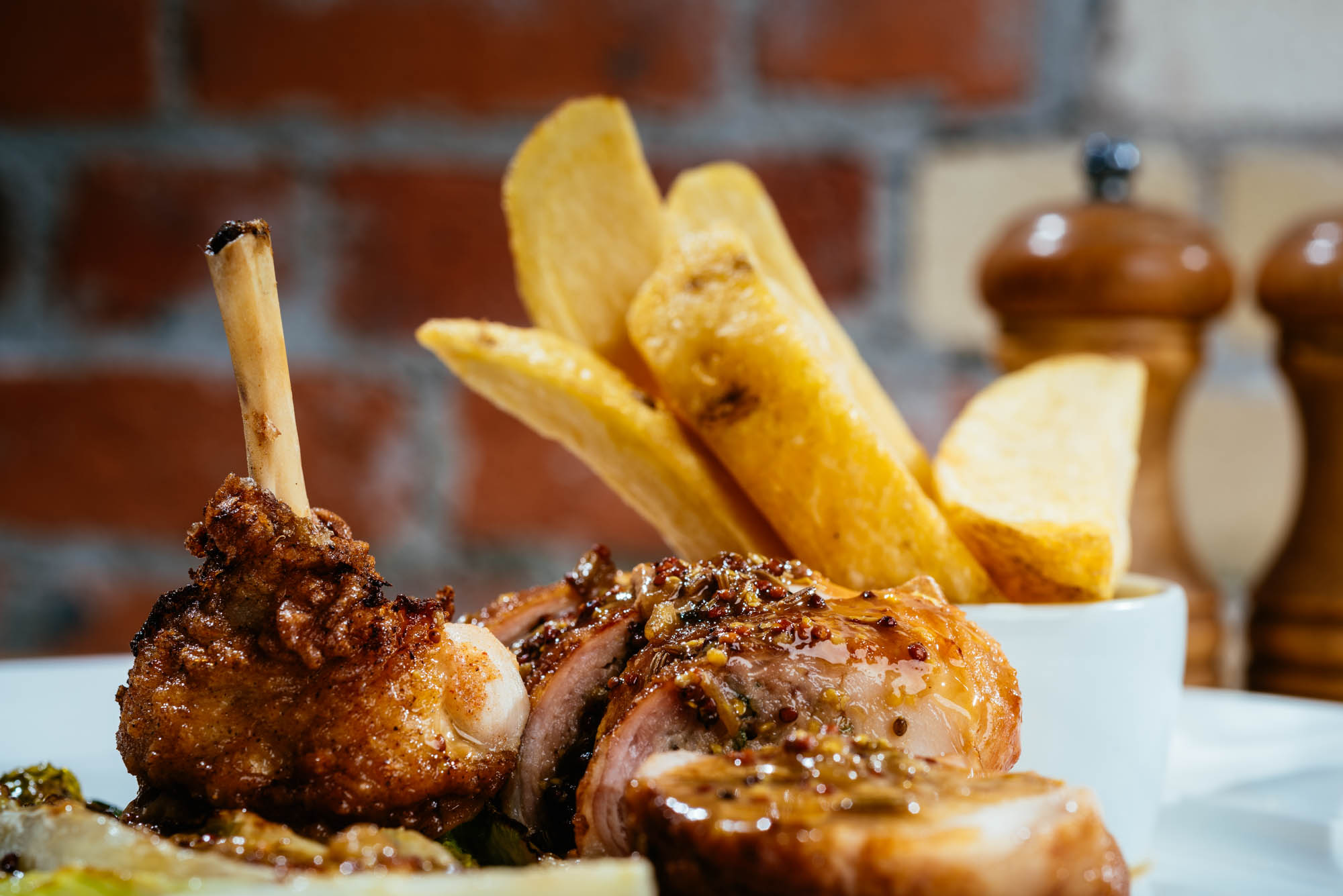 A photo of meat and chips on a plate in front of a red brick wall